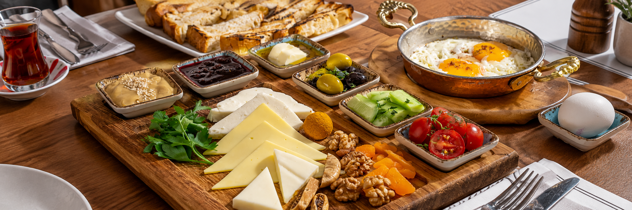A breakfast table with eggs, cheese, vegetables and fresh bread